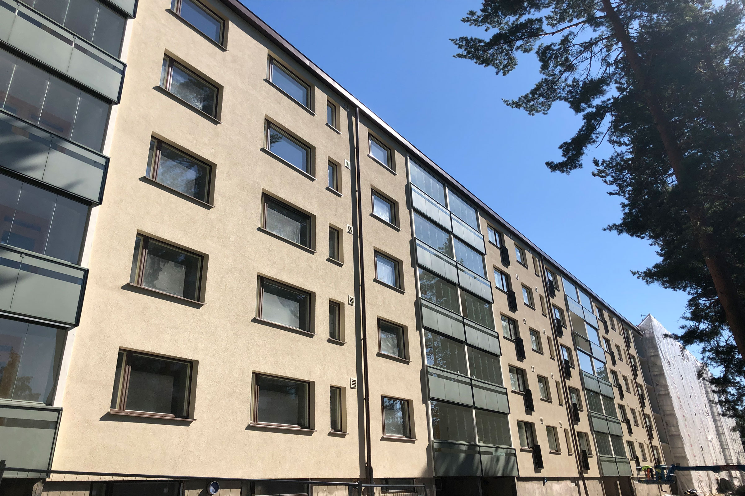 Vaalean ruskea kerrostalo, harmaat parvekkeet parvekelaseilla.