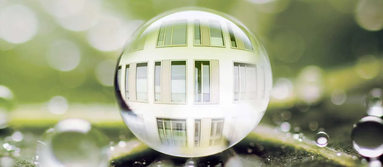 Vesipisara, josta heijastuu talon julkisivu