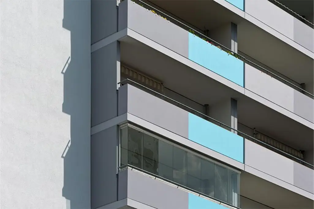 Lähikuva harmaalla ja turkoosilla maalatuista kerrostalon parvekkeista ulkoapäin.
