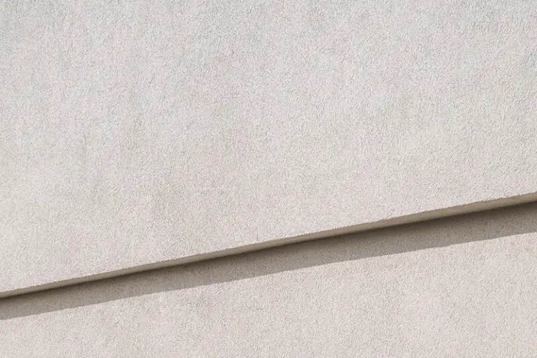 Yksityiskohta vaaleasta, rapatusta julkisivusta.