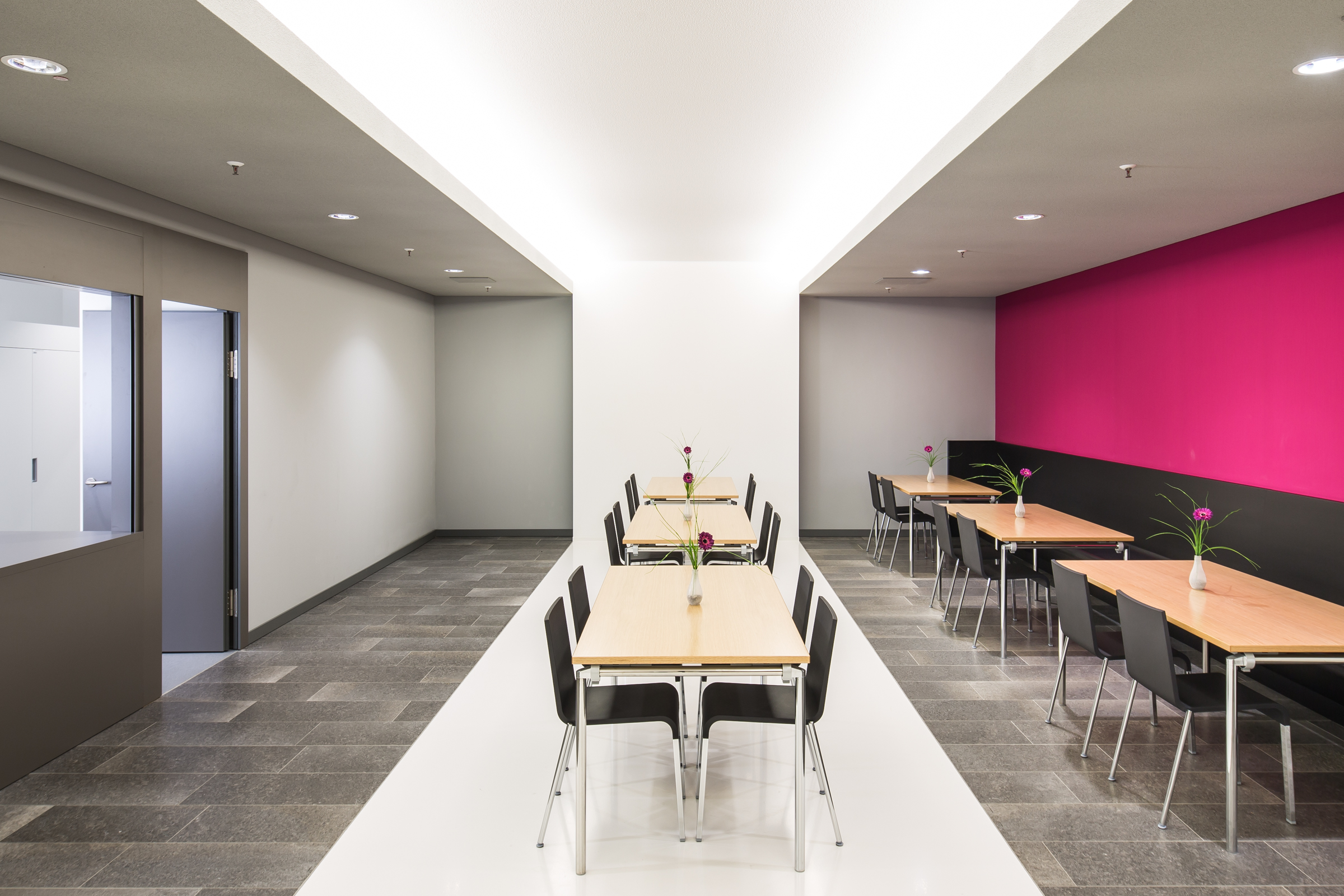 Neuvotteluhuone, jossa pöytäryhmiä tuolineen keskellä huonetta ja oikeanpuoleisella seinällä.