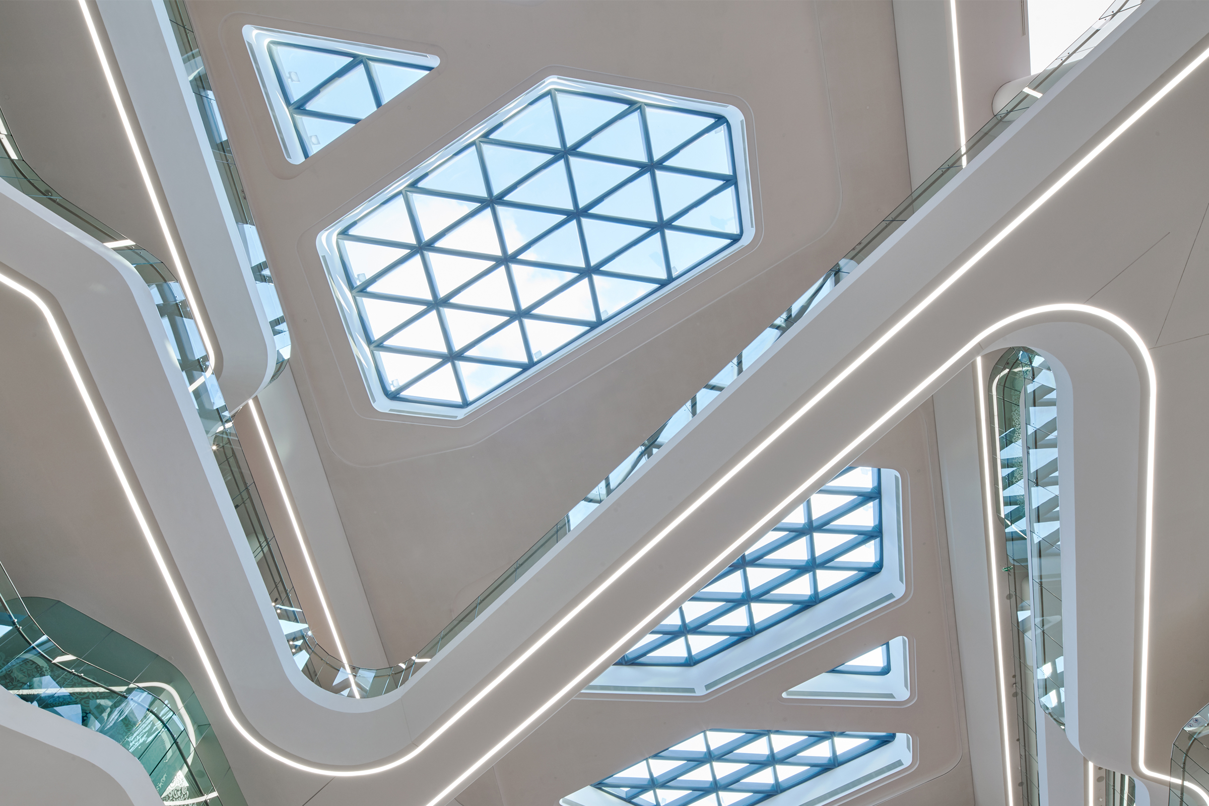 Akustinen katto valkoisilla valaistuilla moduuleilla ja lasikattoilla.