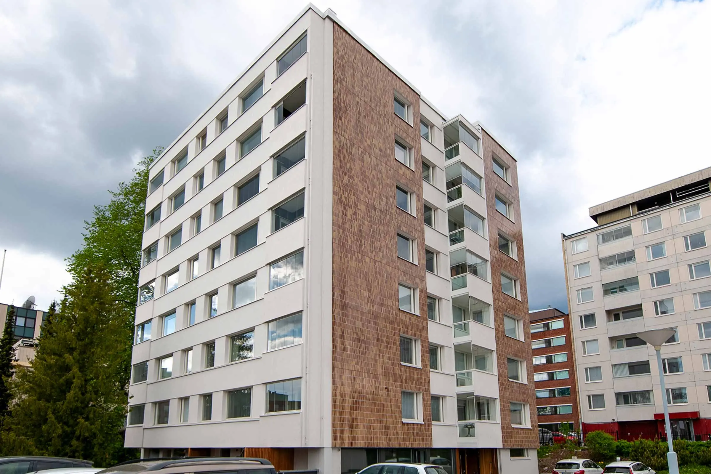 Julkisivukorjattu kerrostalo, jossa keraamista laattaa sekä valkoista rappauspintaa.