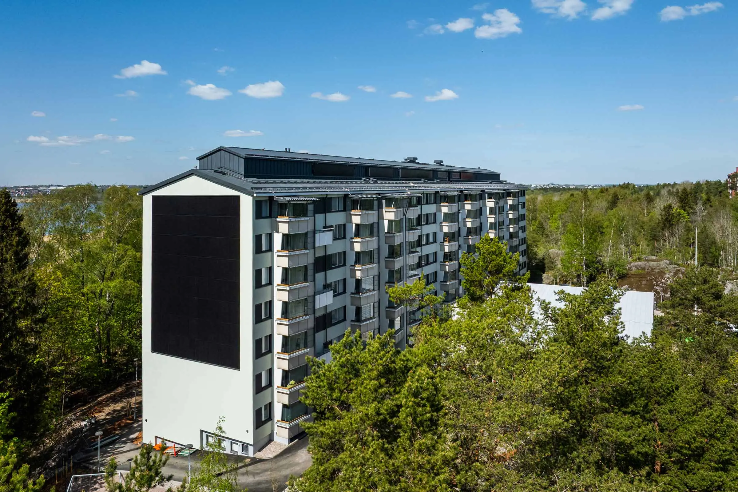 Aurinkopaneelit julkisivussa kerrostalon päädyssä