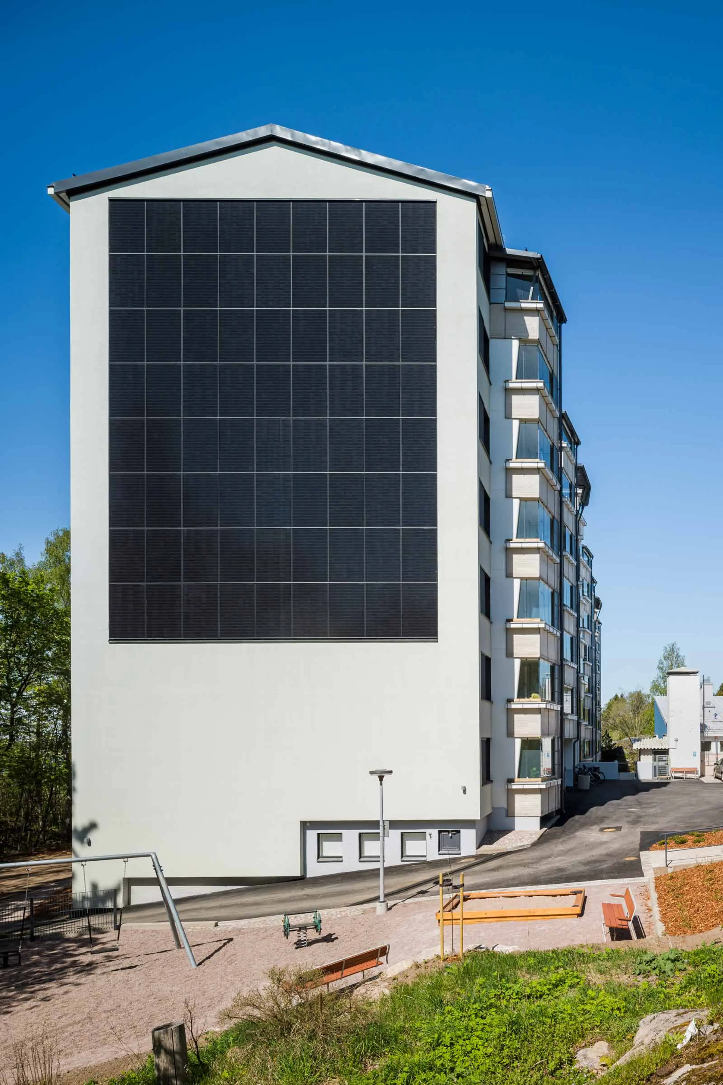Aurinkopaneelit julkisivussa kerrostalon päädyssä