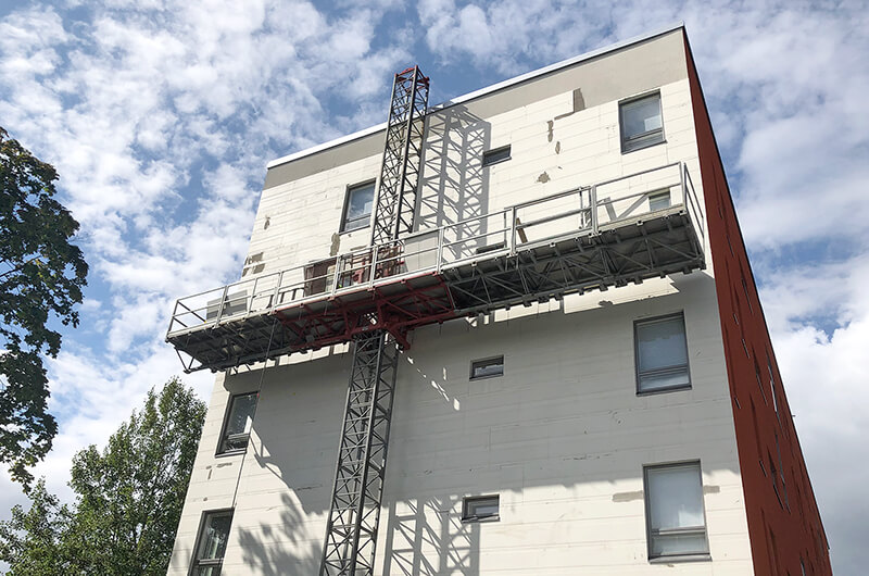 Kerrostalon julkisivu, jonka edessä on rakennusteline. Seinään on asennettu StoReno-rappauslevyjä 