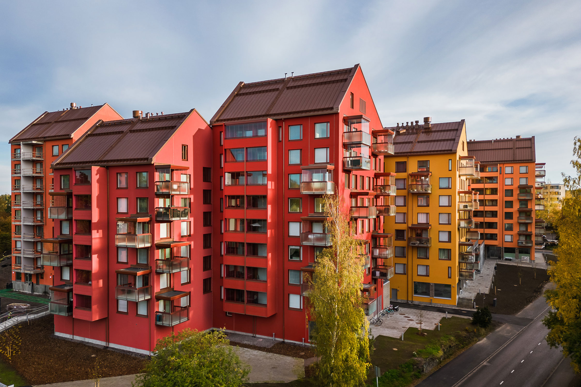 Ilmakuva asuinalueesta, jossa on punaisen, oranssin ja keltaisen sävyisiä kerrostaloja.