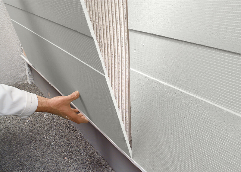 Lähikuvassa käsi tukee StoReno-levyn alaosaa, kun sitä asetetaan alustaa vasten.